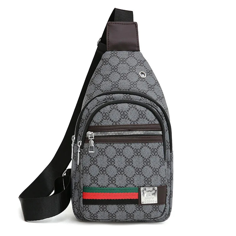 A gray patterned sling bag with brown leather strap and red, green, and black trim.