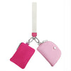 A pink mini zip around wristlet wallet with a white strap and silver chain.