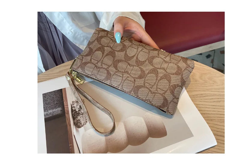 A brown crocodile print zipper long multi-card wallet is shown lying on a white tray with some beige cosmetic products.