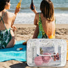 A clear waterproof makeup organizer bag with a white strap and various cosmetic items is shown on a sandy beach.