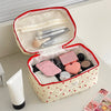 A pink quilted makeup bag with a red trim is open, revealing various cosmetic products inside.