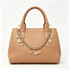 A tan leather handbag with a gold chain and flower pearl charm extension necklace.