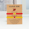 A set of two beaded friendship bracelets with 'I love you' messages and heart charms presented in a kraft paper card.