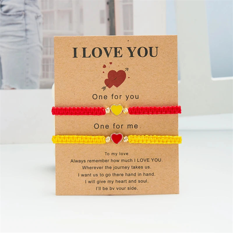 A set of two beaded friendship bracelets with 'I love you' messages and heart charms presented in a kraft paper card.