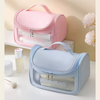 Une trousse de toilette transparente bleu clair et imperméable suspendue à côté d'une rose sur une surface blanche.