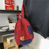 A red and blue canvas fashion backpack hanging on a shelf next to a Coca-Cola sign.