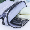 Un sac de toilette imperméable pour voyage, violet et gris, ouvert montrant une peigne en métal noir à l'intérieur.