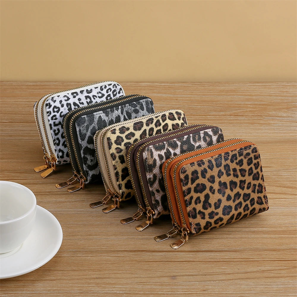 A row of leopard print PU leather compact wallets in various shades and patterns displayed on a wooden surface.
