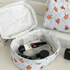 A white cosmetic makeup bag with a striped pattern is open, revealing various makeup and grooming tools inside.