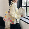 A person holds a white canvas bag and a black strap, next to a window.