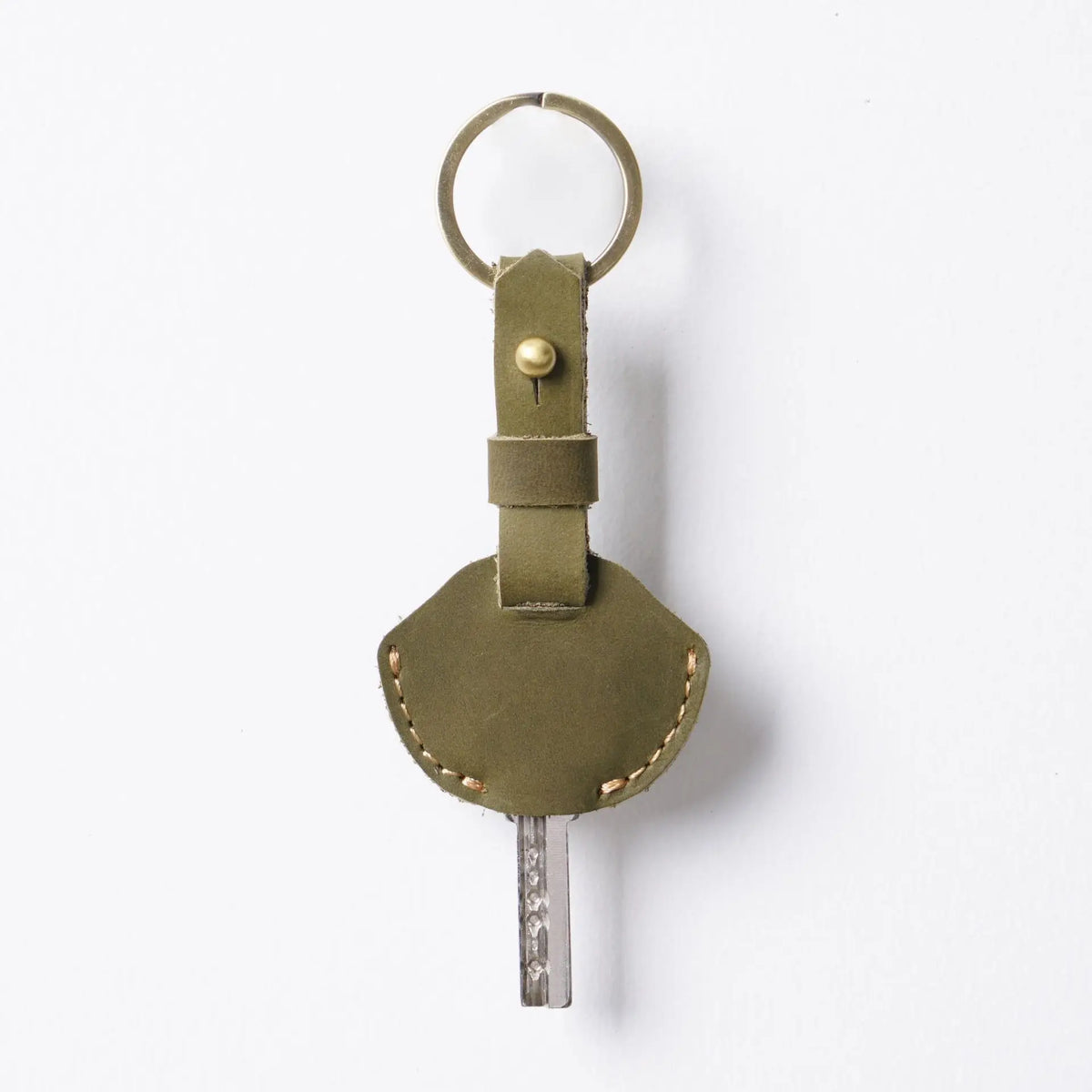 A genuine leather key fob cover with a keychain ring and a metal key attached.