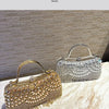 An elegant diamond rhinestone evening clutch bag with a golden tassel resting on a marble surface.