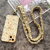 Elegante goldene Schlüsselkette mit geflochtenem Gold- und Cremkord neben einem Telefon.