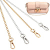 A collection of adjustable gold and silver chain straps for handbags, including a pink leather purse.