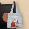 A light blue canvas shoulder bag featuring a Snoopy cartoon design with a red house and a pink pig.