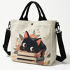 Beige Tasche mit schwarzer Katzen- und floraler Druck und schwarzem Riemen.