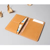 A brown genuine cowhide leather passport and ticket holder with a stitched design resting on a gray surface.