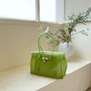 Limetgrüne Sommer-Jelly-Shoulderbag mit weißem Riemchen, auf einer hellen Oberfläche am Fenster.