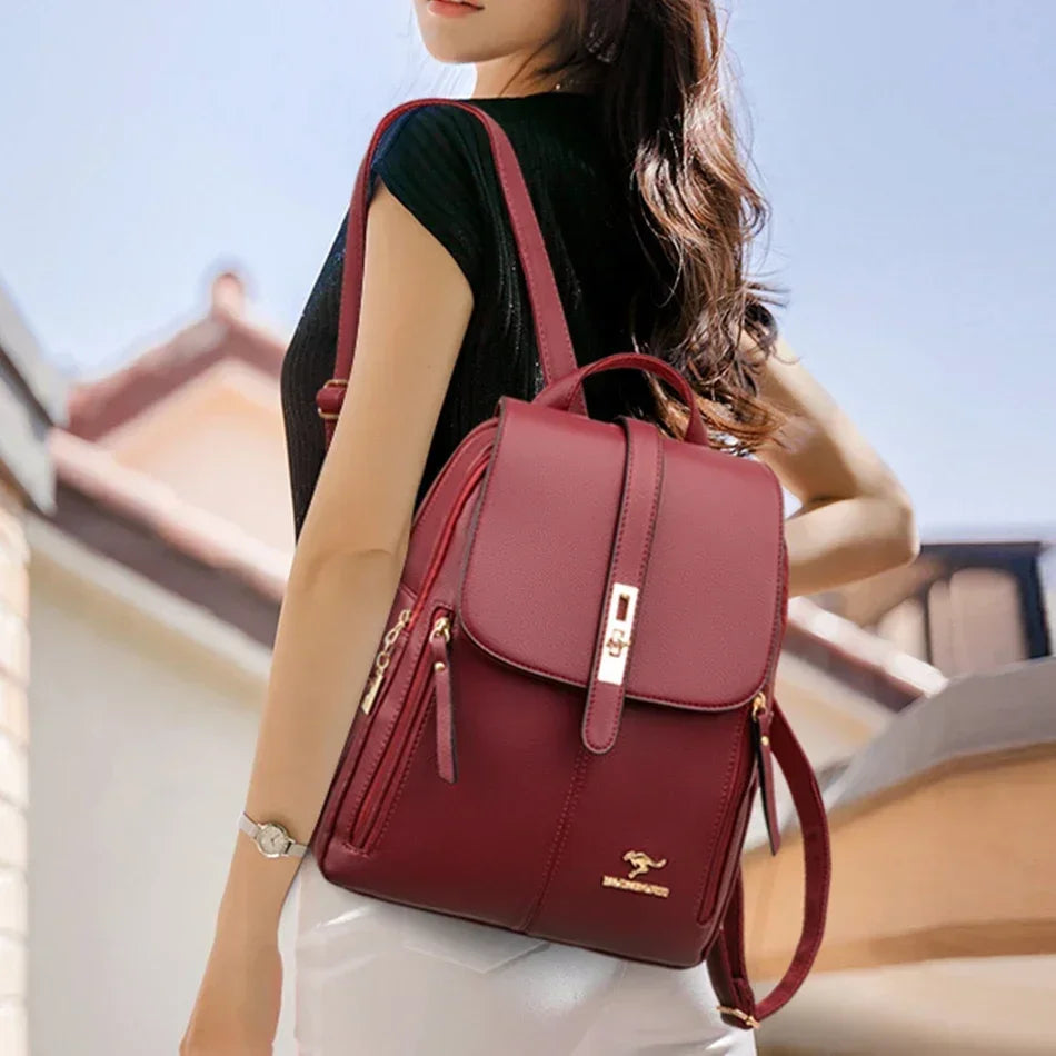 Une femme tient un sac à dos en cuir microfibre marron avec des accents dorés contre un ciel lumineux.
