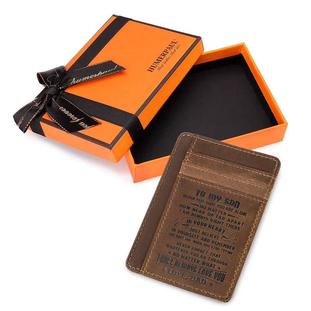 Une boîte cadeau orange avec un ruban noir et un portefeuille en cuir marron à l'intérieur.