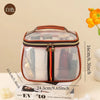 A clear waterproof travel toiletry bag with a brown and black trim resting on a stack of books.