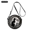 A black cartoon cat round crossbody bag with intricate circular design and a long strap.