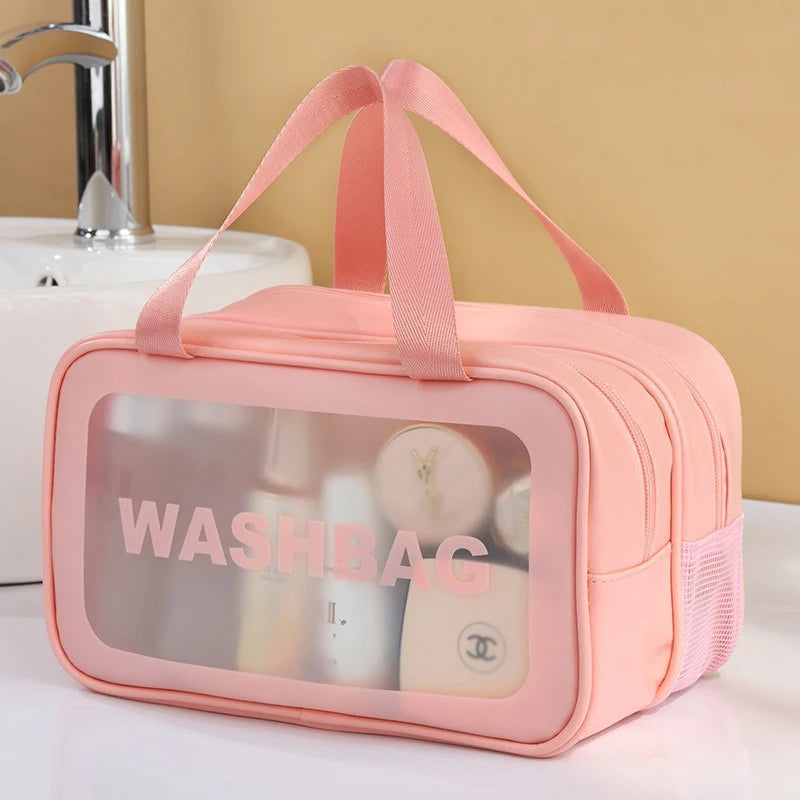 A pink clear plastic travel toiletry bag with a pink ribbon closure, showing various toiletries inside.