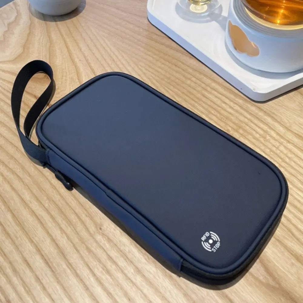 A dark blue waterproof RFID blocking passport holder lying on a light wooden surface.