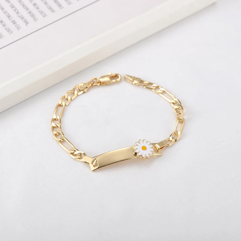 A gold-colored chain bracelet with a white daisy charm, displayed on a white background.