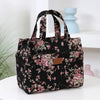 A black cloth tote bag with a pink floral pattern is displayed on a white surface.