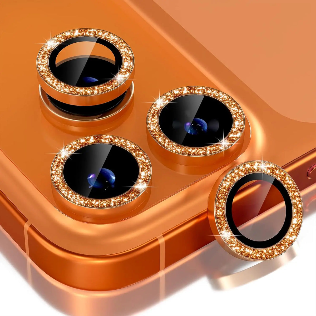 A close-up of a copper-colored camera lens protector with a metal frame and glitter diamond surface for an iPhone.