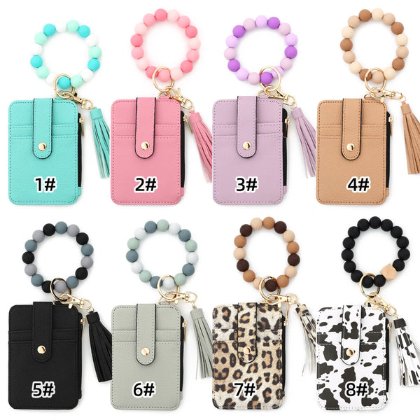 Eight numbered leather card holders in various colors and leopard print patterns with gold keychains and bangles