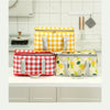 Three insulated picnic totes in yellow, red, and light green patterns are displayed on a white countertop.