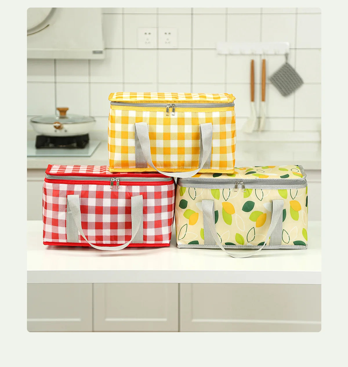Three insulated picnic totes in yellow, red, and light green patterns are displayed on a white countertop.