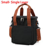 A black insulated lunch bag with brown straps and a zippered pocket.