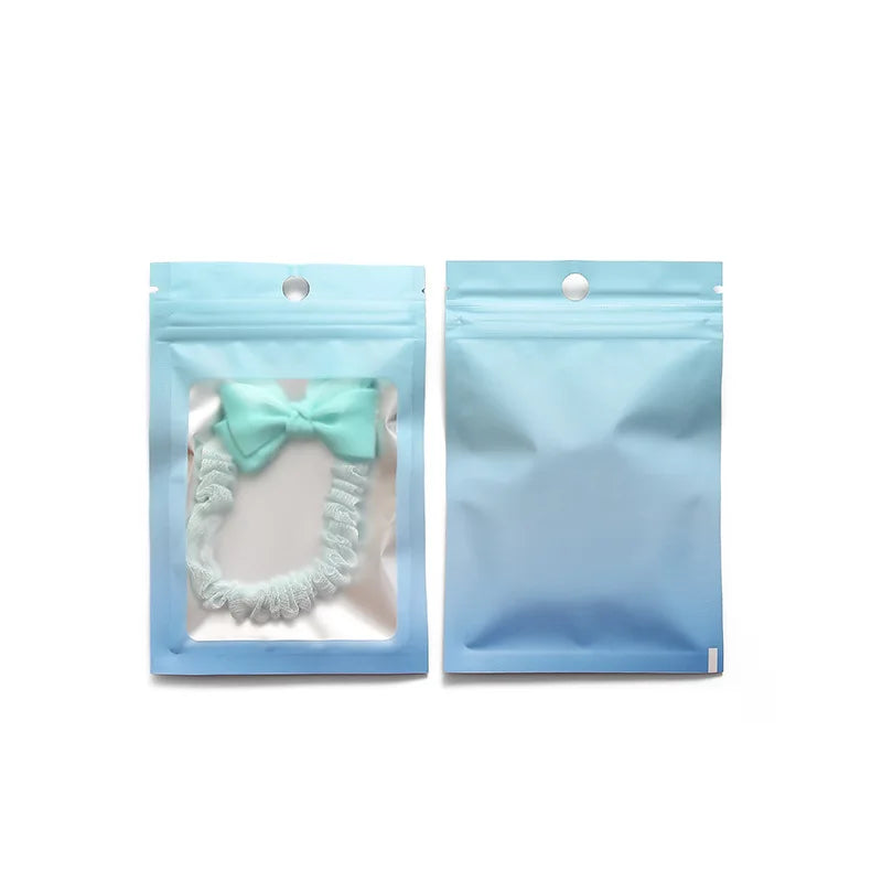 Two light blue resealable storage bags containing a mint green bow and a white beaded necklace.