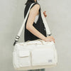 A woman is holding a cream-colored quilted travel duffle bag with white straps against a light gray background.