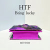 A magenta clutch bag with purple sequin embroidery is displayed against a white background.