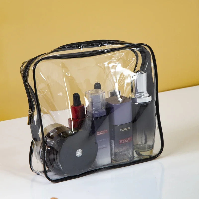 A clear PVC travel toiletry bag set containing three black and purple beauty products on a white surface.