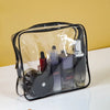 A clear PVC travel toiletry bag set containing three black and purple liquid bottles.