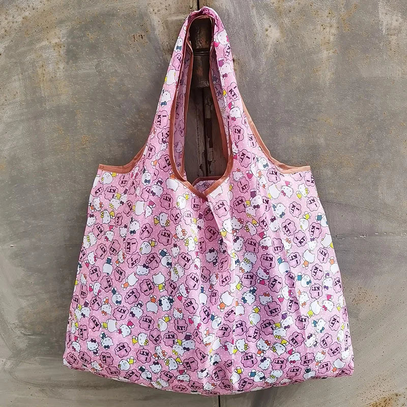 A pink patterned reusable shopping bag hanging against a gray concrete wall.