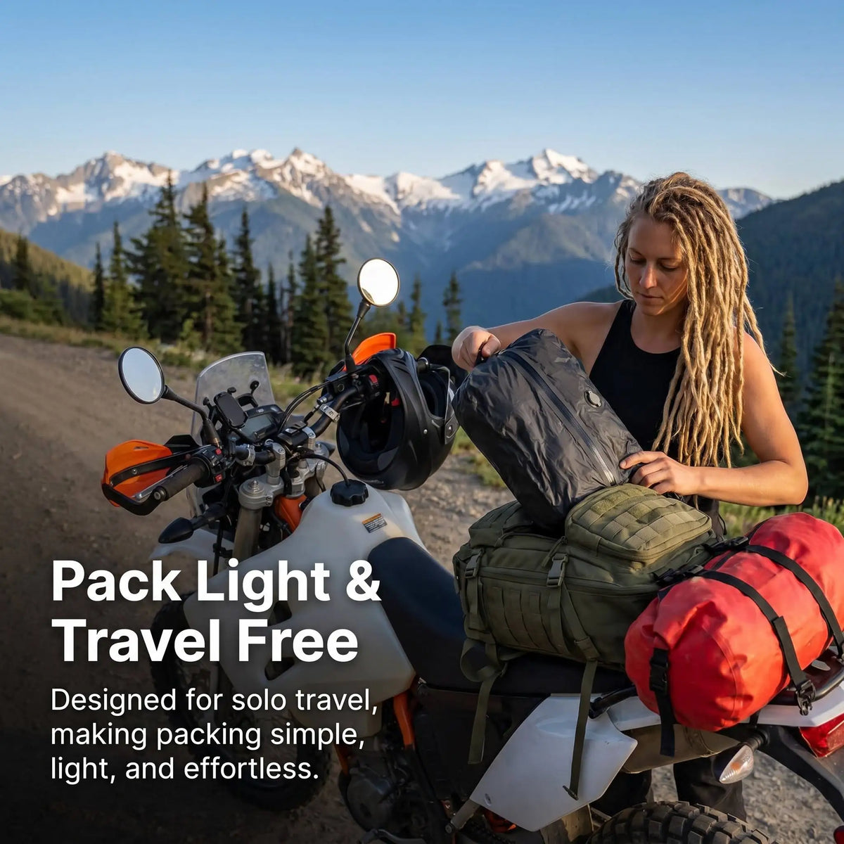 A woman is packing a black vacuum storage bag onto the seat of an orange motorcycle in a mountainous outdoor setting.