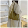 Beige Trenchcoat mit olivgrüner Canvas-Tasche über der Schulter.
