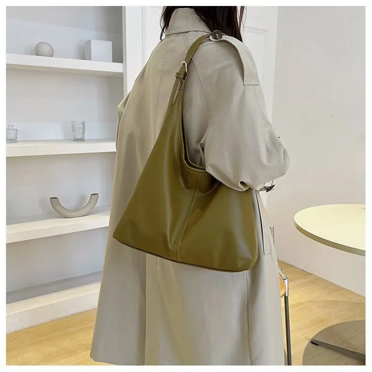 Beige Trenchcoat mit olivgrüner Canvas-Tasche über der Schulter.