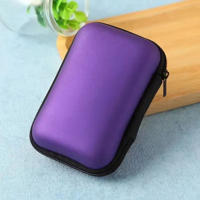 Sac de rangement portable violet pour appareils électroniques et câbles, posé sur une surface en bois.