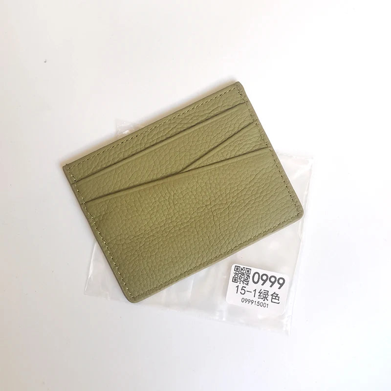 Porte-cartes en cuir vert avec gravure diagonale dans un emballage plastique transparent.