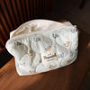 A white quilted cosmetic storage pouch featuring small printed cats on the exterior.