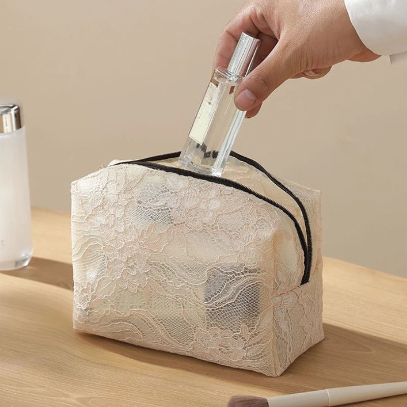 A hand is placing a glass bottle into a square, sheer lace mesh organizer bag.