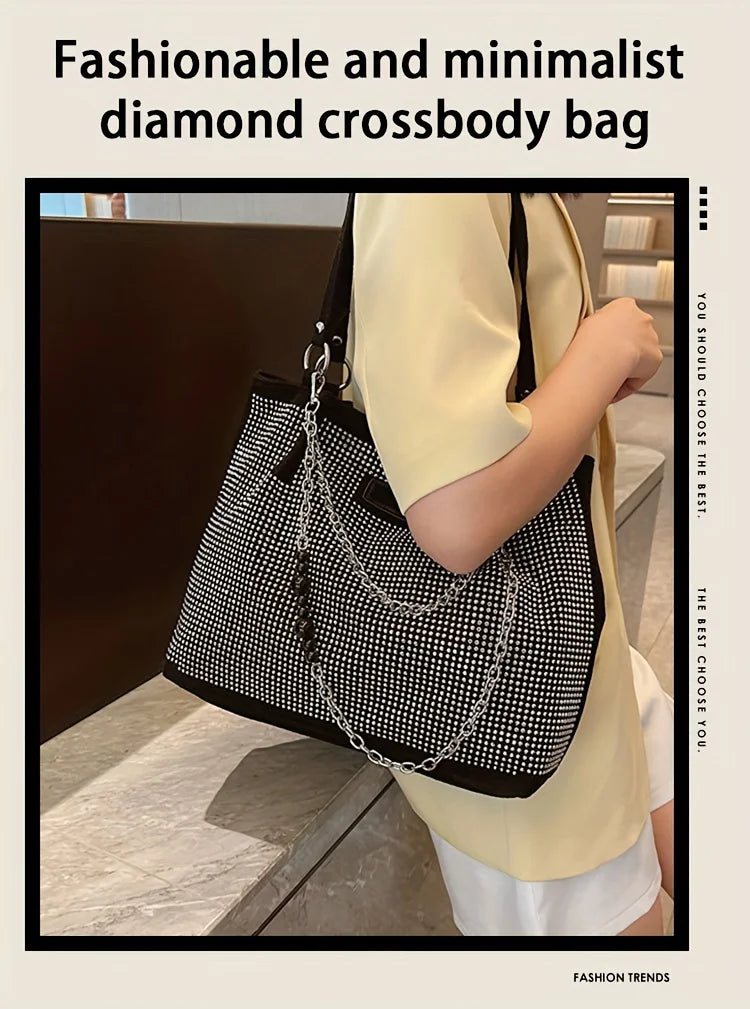 Eine Frau hält eine schwarze Diamant-Crossbody-Tasche mit silberner Kette vor einem hellgelben Hemd.