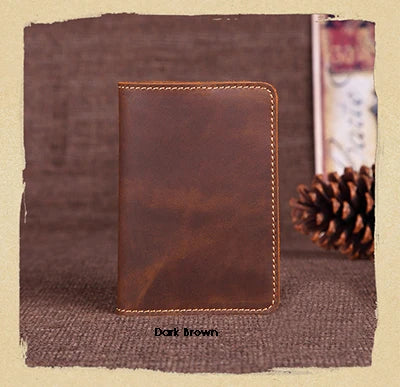 A dark brown genuine leather passport wallet with card holders resting on a textured brown surface.